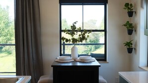 Une cuisine avec une fenêtre, un vase avec des plantes et une vue sur la verdure à l’extérieur.