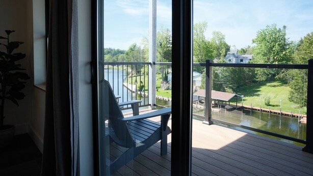 A balcony with a view of a lake, a chair, and a small dock area.