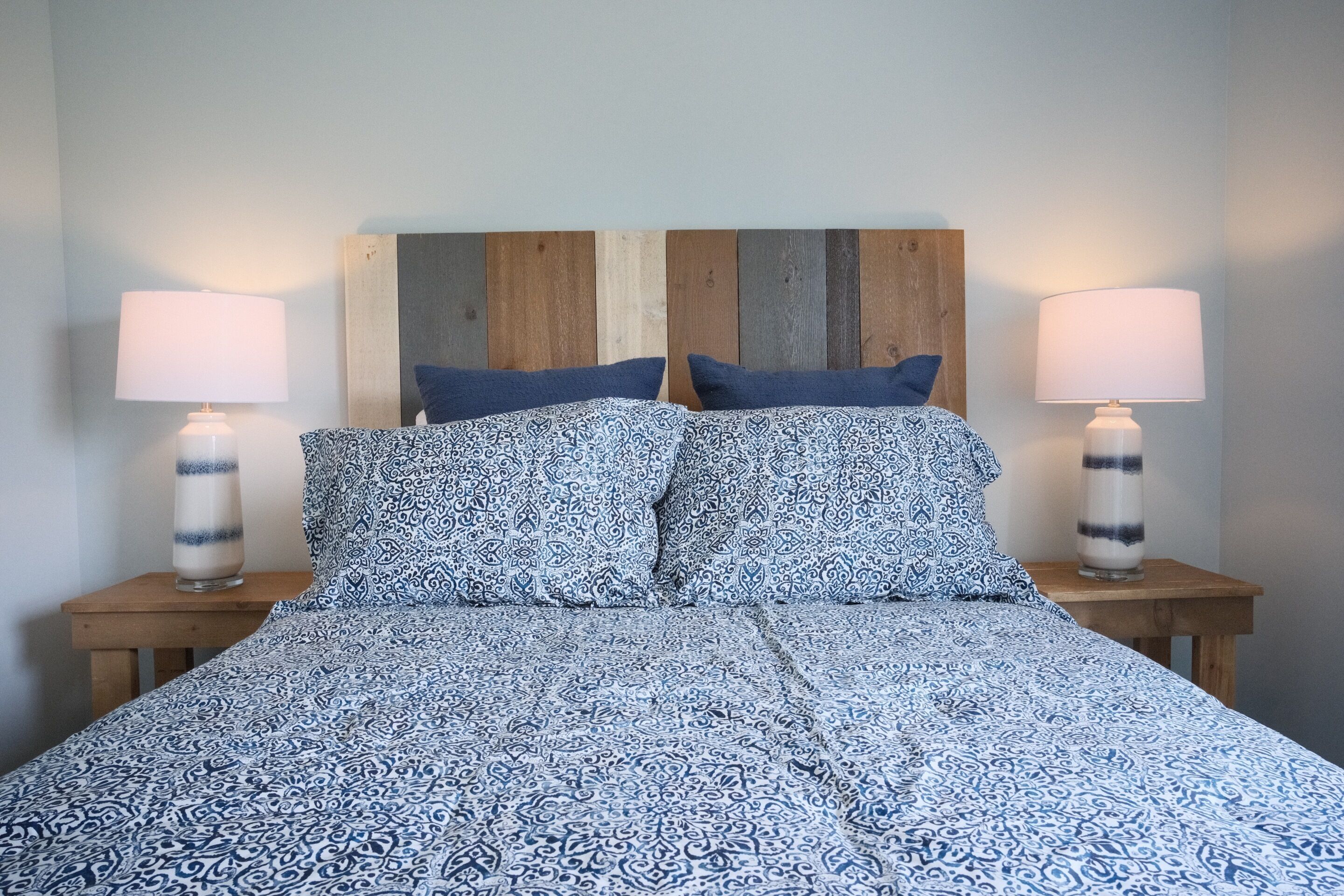 A bed with a patterned bedspread, two bedside lamps, and a wooden headboard.