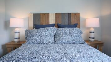 A bed with a patterned bedspread, two bedside lamps, and a wooden headboard.