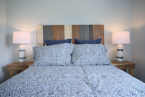 A bed with a patterned bedspread, two bedside lamps, and a wooden headboard.