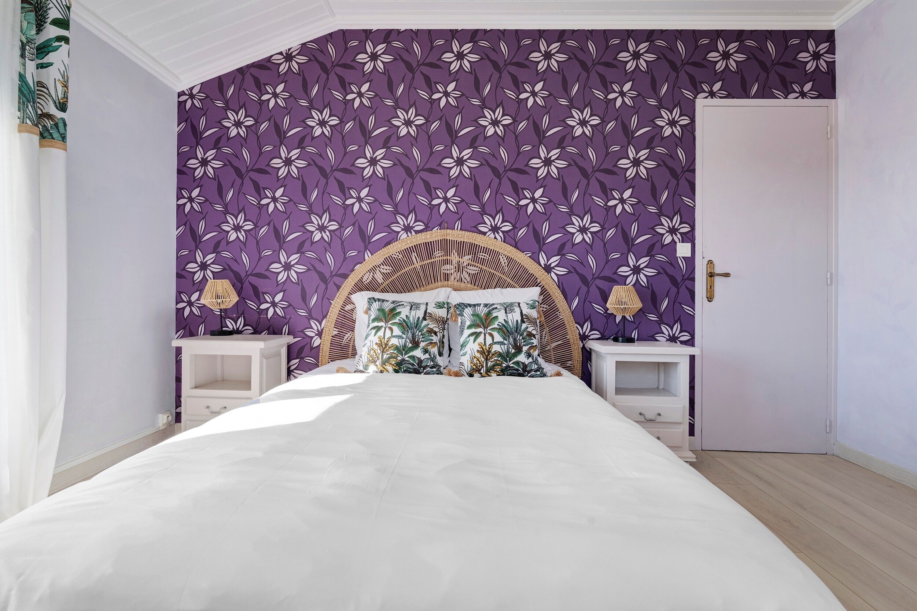 A bedroom with a bed, a headboard, two bedside tables, and a door.
