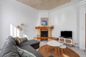 Una sala de estar con chimenea, televisor, sofá y una mesita.