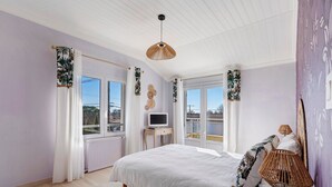 Ein Schlafzimmer mit einem Bett, einem Fernseher auf einem kleinen Tisch und einem Fenster mit Vorhängen.