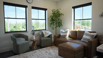 A living room with a sofa, armchair, and a large window.