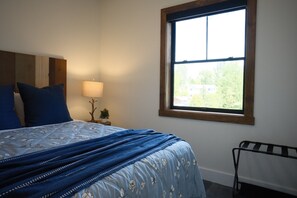 A bedroom with a bed, a window, a nightstand, a lamp, and a radiator. - New 2BR River Condo w/ Balcony (Indian River)