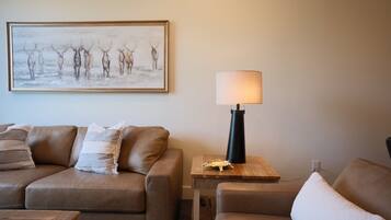 A living room with a brown leather sofa, a wooden side table with a lamp, and a framed picture on the wall.