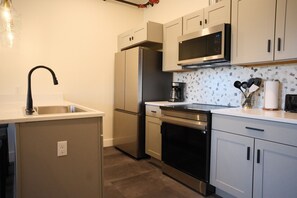 A modern kitchen with stainless steel appliances, a microwave, and a coffee maker. - New 2BR River Condo w/ Balcony (Indian River)