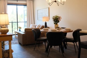 A dining area with a table set for four, a sofa, and a lamp. - New 2BR River Condo w/ Balcony (Indian River)