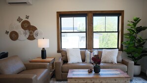A living room with a sofa, a coffee table, a lamp, decorative wall art, and a window.