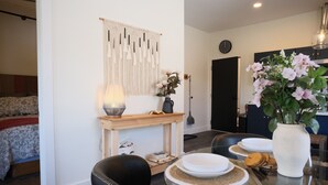 A dining area with a glass table, plates, and a vase of flowers.