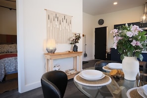 A dining area with a glass table, plates, and a vase of flowers.