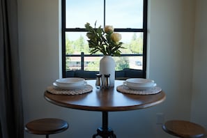 A dining table with two white plates, a vase with flowers, and salt and pepper shakers.