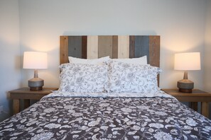 A bed with a floral-patterned bedspread, wooden headboard, and two bedside lamps.