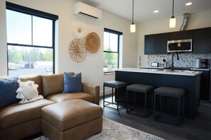A modern kitchen with a microwave, bar stools, and a large window.