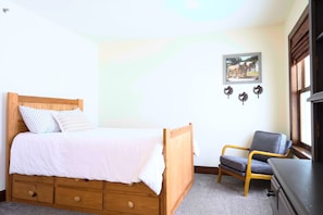 A bedroom with a wooden bed, a chair, a dresser, and a picture on the wall.