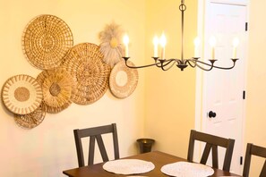 Un comedor con mesa, sillas, una araña y adornos tejidos en las paredes.