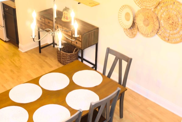 Una mesa de comedor con manteles individuales blancos, una araña y una cesta sobre la mesa.