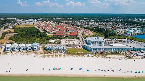 Luftaufnahme einer Küstenstadt mit Strandhotels, einem großen Resort und einer Marina.