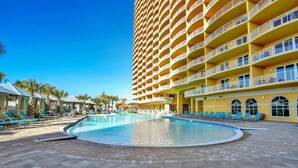 Un hotel con un amplio área de piscina, varios balcones y palmeras.