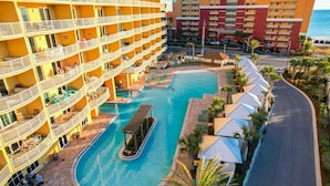 Ein Hotel mit mehreren Balkonen, einem zentral gelegenen Pool und einer Zufahrt zum Strand.