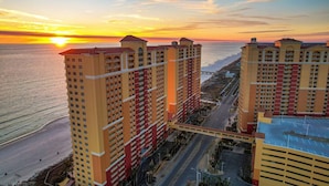 Ein Hochhaus mit mehreren Etagen, einer zentralen Fußgängerbrücke und Blick auf den Strand bei Sonnenuntergang.