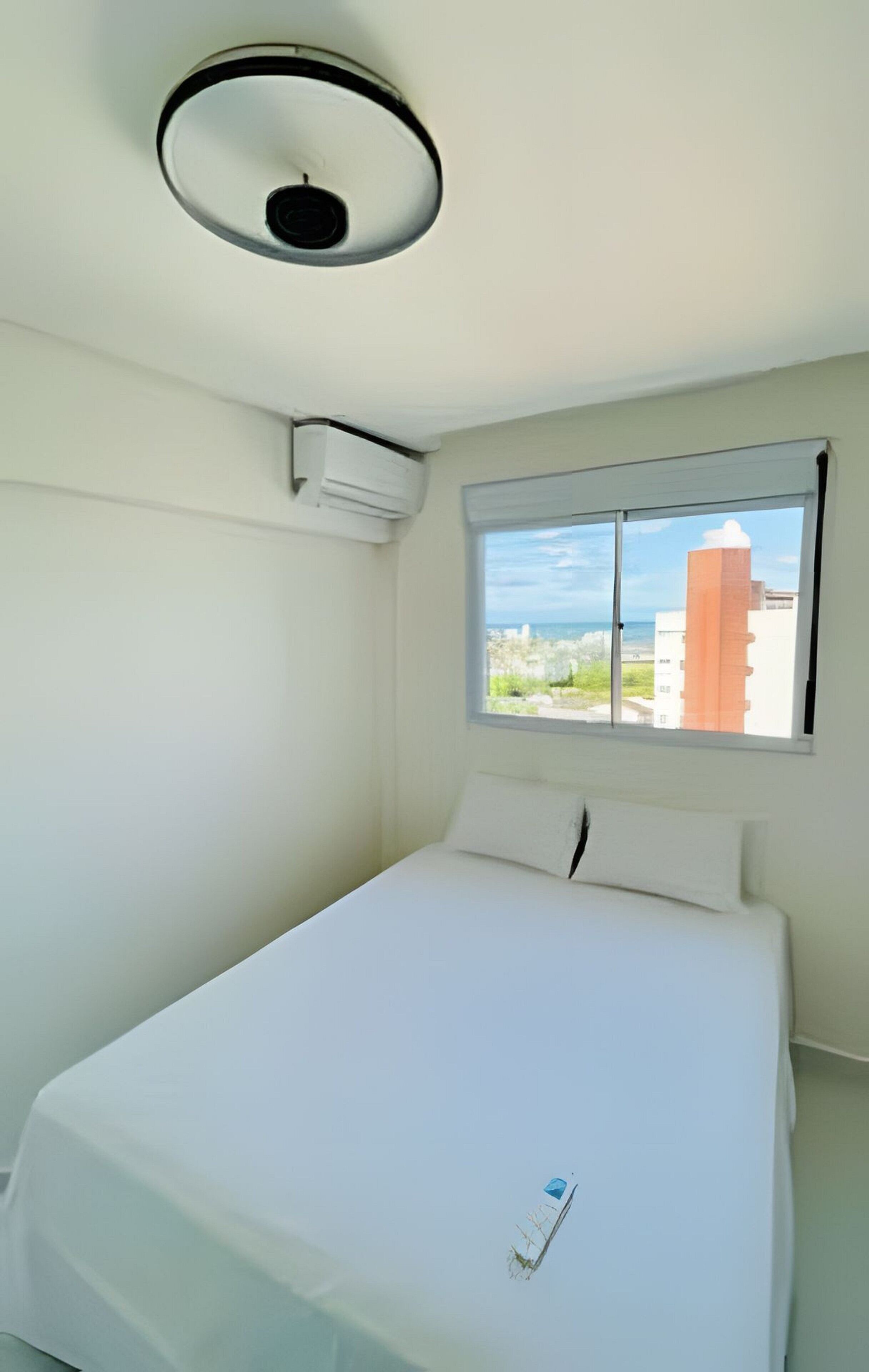 Ein Zimmer mit Bett, Fenster und Deckenleuchte.