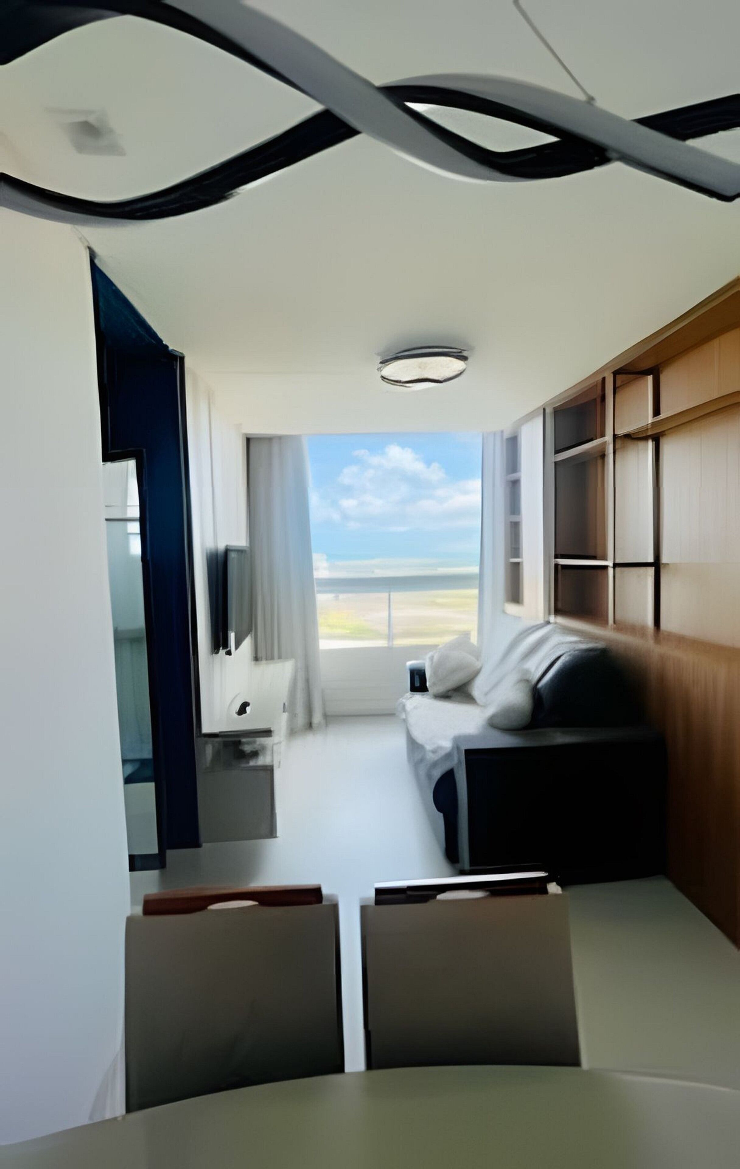 Ein modernes Zimmer mit einem Bett, einem Fernseher, einem Schreibtisch und Blick ins Freie.
