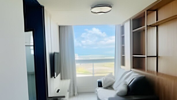 Una habitación moderna con cama, televisor, escritorio y vistas al exterior.