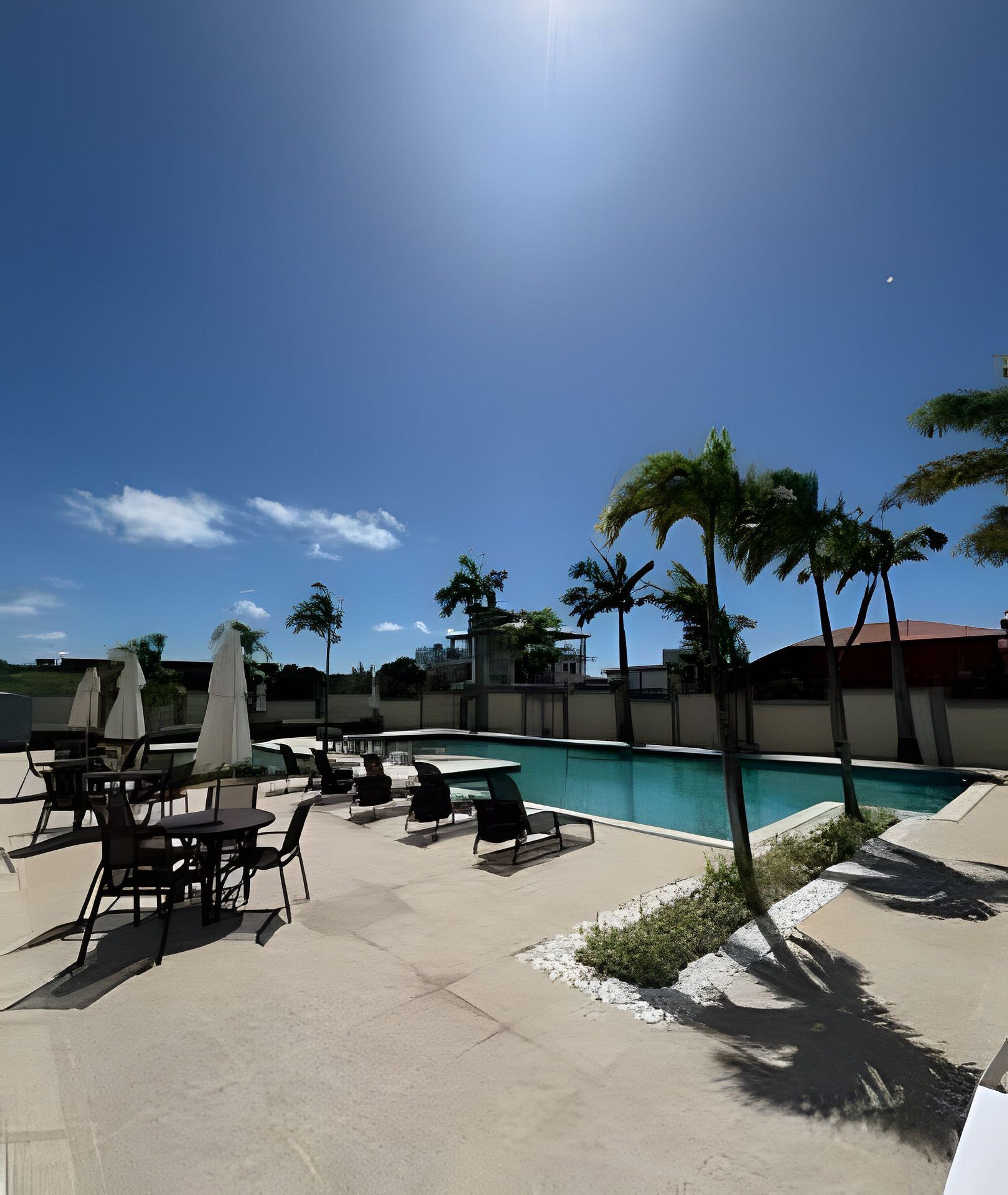 A poolside area with lounge chairs, umbrellas, and a clear blue sky.