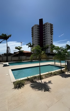 A swimming pool with a view of a tall building in the background.