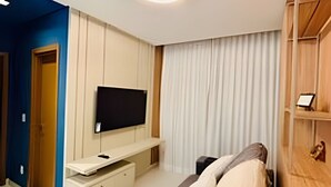 Une chambre d’hôtel moderne, équipée d’un lit, d’un téléviseur fixé au mur, d’une armoire en bois et d’une porte donnant sur une autre pièce.