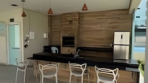 Une cuisine moderne avec un mur d’accent en bois, des appareils en acier inoxydable et des chaises blanches.