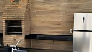 Une cuisine moderne avec une cheminée en pierre, un réfrigérateur en acier inoxydable et des chaises blanches.
