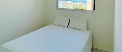 Una habitación pequeña y limpia con una cama, una ventana con vistas y una lámpara en el techo.