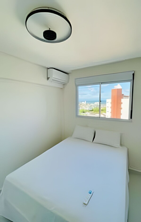 A bedroom with a bed, a window with a view, and an air conditioning unit. - 1501 Apto2 Qtos Vista Mar (Cabedelo)