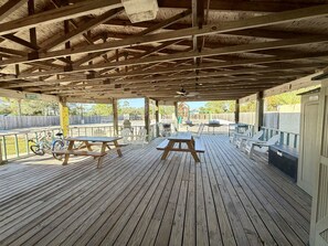 A covered outdoor area with picnic tables and chairs, a bicycle, and a wooden deck. - Gulf Shores - Village by the Gulf 2/2 *balcony* (Gulf Shores)