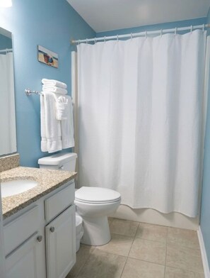 A bathroom with a toilet, sink, and a shower curtain. - Gulf Shores - Village by the Gulf 2/2 *balcony* (Gulf Shores)