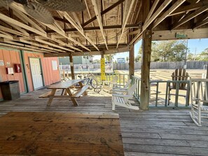 A wooden deck with picnic tables and chairs, a bicycle, and a wooden fence. - Gulf Shores - Village by the Gulf 2/2 *balcony* (Gulf Shores)