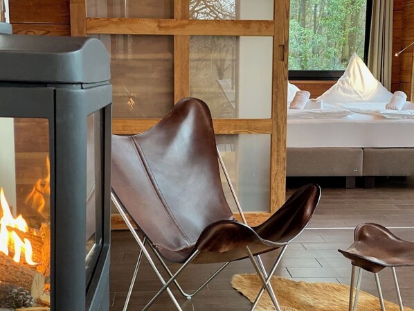 Una habitación acogedora con chimenea, una cama con sábanas blancas y modernas sillas de cuero.