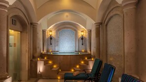 Un área de spa con un jacuzzi central, dos luces empotradas y dos sillones de descanso a rayas.