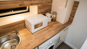 Eine kompakte Küche mit Mikrowelle, Kaffeemaschine und Waschmaschine.