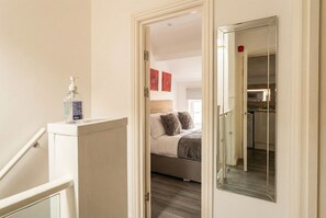 A bedroom with a bed, a nightstand, and a mirror. - Perfectly located home base with paid parking and wifi (Ancoats)