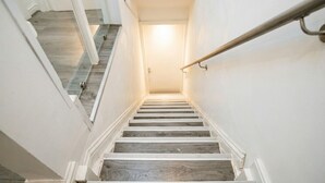 Eine Treppe mit Geländer, aus Holz und mit einer Lampe am oberen Ende.