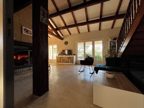 A spacious living area with a fireplace, a sofa, and a kitchen area with a TV. - Beautiful Provençal family home (Saint-Gilles)