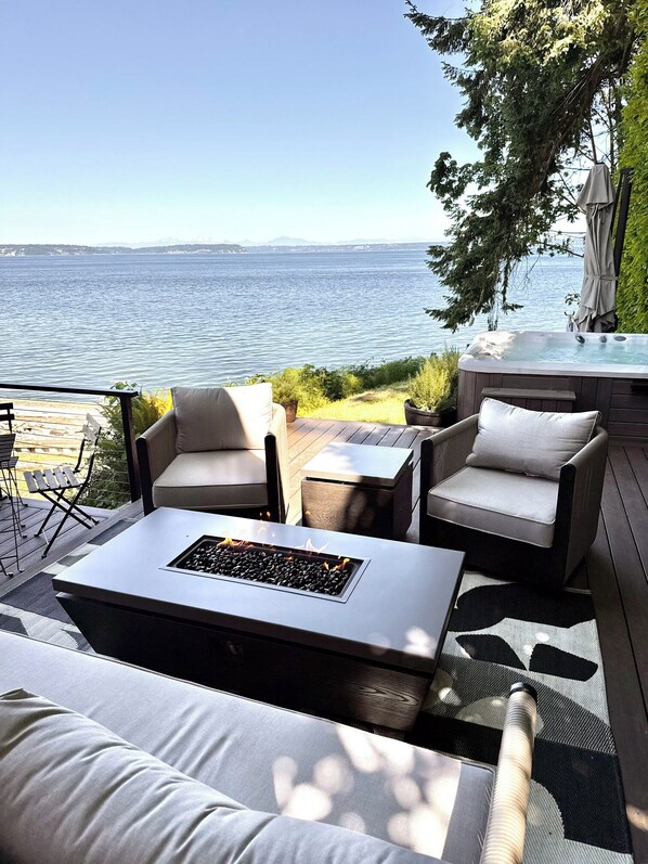 A deck with outdoor furniture, a fire feature, and a view of the water.