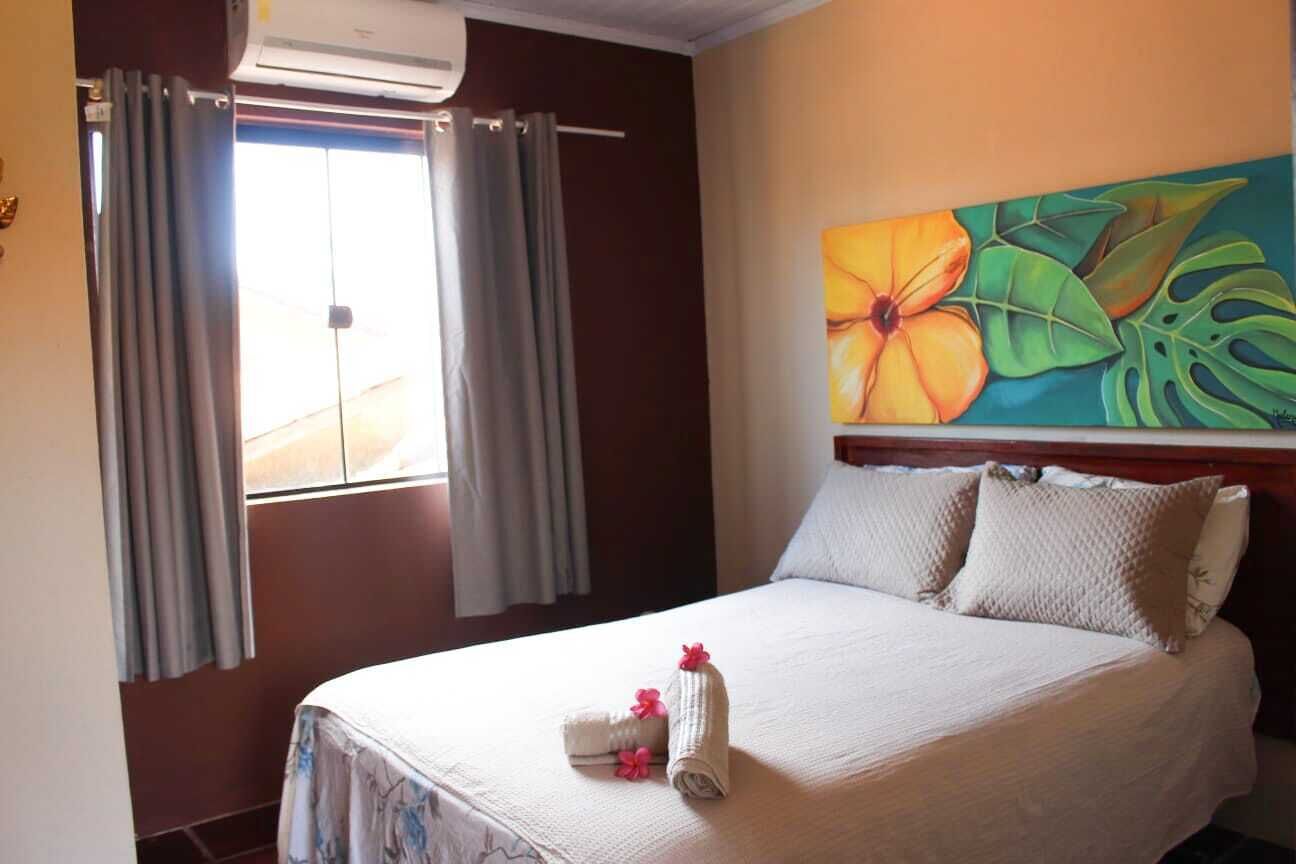 A hotel room with a bed, curtains, a painting, and a window.