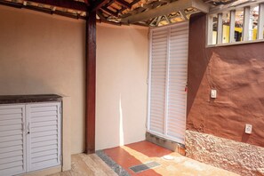 Ein Blick in einen Raum, mit einer weißen Tür, einem Fenster mit weißen Rollläden und einer roten Wand.
