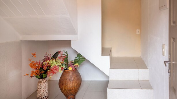 A staircase leading to a landing with a decorative vase of flowers on the landing. - Apartment in downtown Búzios | 2 bedrooms | Air conditioning (Armação dos Búzios)