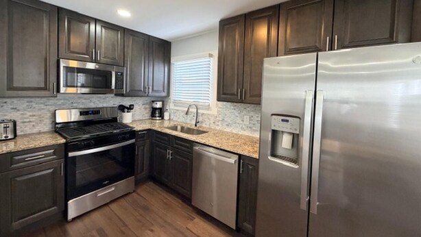 Una cocina moderna con armarios de madera oscura, electrodomésticos de acero inoxidable y encimera de granito.